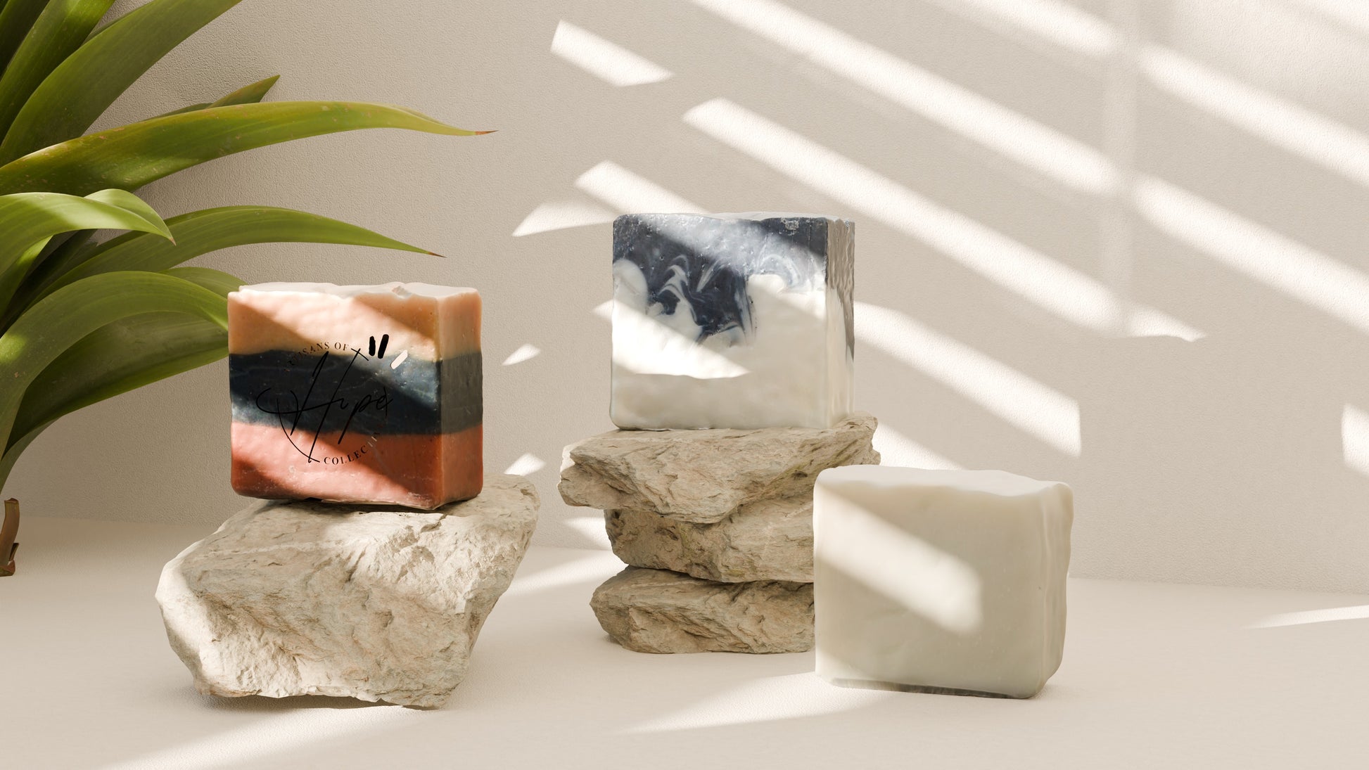 Decorative items including a rectangular object, a cylindrical container, and a square object on a light surface with a plant in the corner.